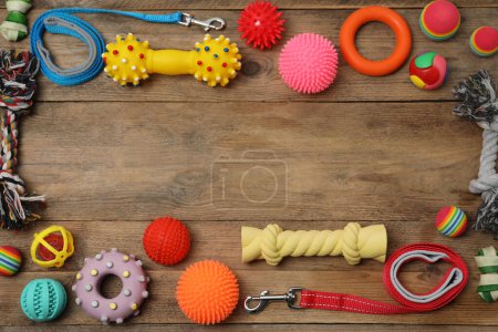 Foto de Composición plana con correas para perros y juguetes sobre fondo de madera, espacio para texto - Imagen libre de derechos