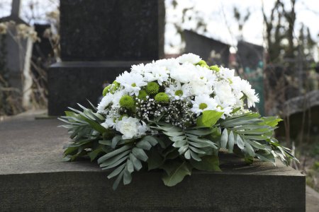 Téléchargez les photos : Couronne funéraire de fleurs sur pierre tombale dans le cimetière - en image libre de droit