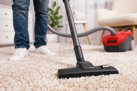 Photo for Man cleaning carpet with vacuum cleaner at home, closeup - Royalty Free Image