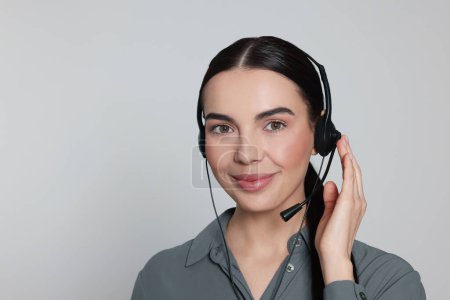 Hotline-Betreiber mit modernem Headset auf hellgrauem Hintergrund. Kundenbetreuung