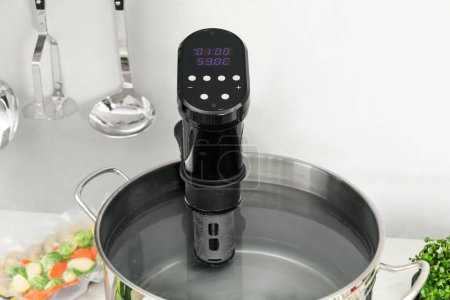 Photo for Sous vide cooker in pot on white table, closeup. Thermal immersion circulator - Royalty Free Image