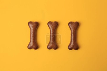 Téléchargez les photos : Biscuits pour chien en forme d'os sur fond orange, plat - en image libre de droit
