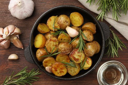 Photo for Delicious baked potatoes with rosemary and ingredients on wooden table, flat lay - Royalty Free Image