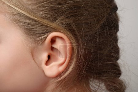 Photo for Closeup view of little girl against light gray background, focus on ear - Royalty Free Image