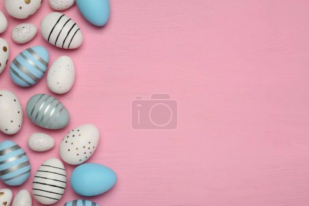 Foto de Composición plana con huevos de Pascua decorados festivamente sobre una mesa de madera rosa. Espacio para texto - Imagen libre de derechos