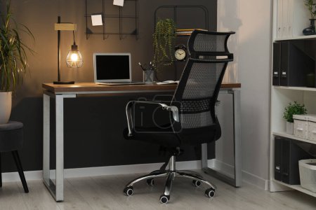 Téléchargez les photos : Lieu de travail confortable avec ordinateur portable moderne sur le bureau et chaise confortable à la maison - en image libre de droit