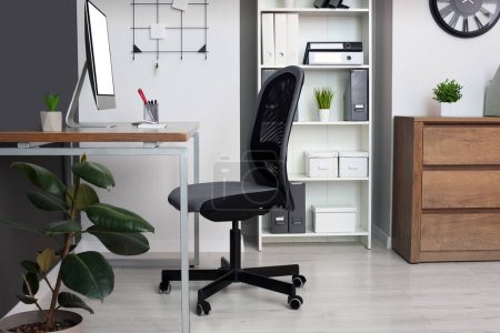 Foto de Elegante interior de oficina con silla cómoda, escritorio y computadora - Imagen libre de derechos