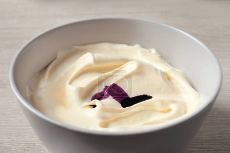 Téléchargez les photos : Bol de crème avec colorant alimentaire violet sur table en bois blanc, gros plan - en image libre de droit
