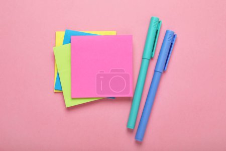 Papiernotizen und bunte Marker auf rosa Hintergrund, flache Lage