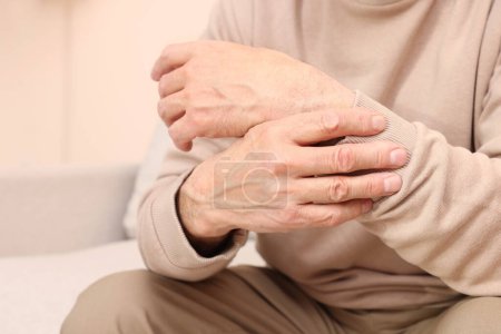 Photo for Senior man suffering from pain in his wrist at home, closeup. Arthritis symptoms - Royalty Free Image