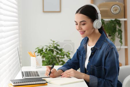 Photo for Woman in headphones studying on laptop at home. Online translation course - Royalty Free Image
