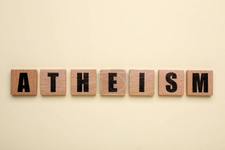 Téléchargez les photos : Mot Athéisme fait de carrés en bois avec des lettres sur fond beige, vue de dessus - en image libre de droit