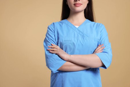 Photo for Nurse in medical uniform on light brown background, closeup. Space for text - Royalty Free Image