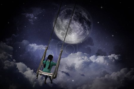 Somnambulisme. Fille sur swing dans ciel nocturne avec pleine lune