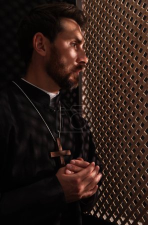 Foto de Sacerdote católico con sotana en cabina confesional - Imagen libre de derechos