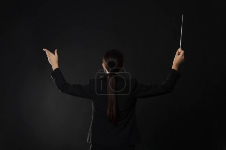Foto de Conductor profesional con bastón sobre fondo oscuro, vista trasera - Imagen libre de derechos