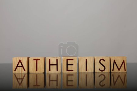 Photo for Word Atheism made of wooden cubes with letters on mirror surface - Royalty Free Image