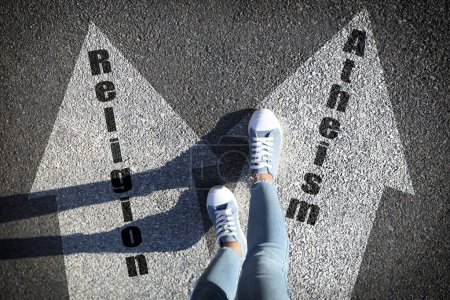 Photo for Philosophical or religious position. Woman standing on road marking arrow with word Atheism, closeup - Royalty Free Image