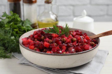 Schüssel mit leckerem frischen Vinaigrette-Salat auf weißem Holztisch, Nahaufnahme