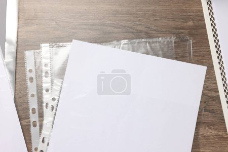 Photo for Punched pockets with paper sheet on wooden table, flat lay - Royalty Free Image