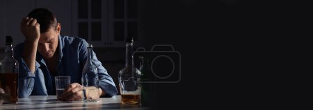 Téléchargez les photos : Souffrant de gueule de bois. Homme avec boisson alcoolisée à table dans la cuisine, espace pour le texte. Conception de bannière - en image libre de droit