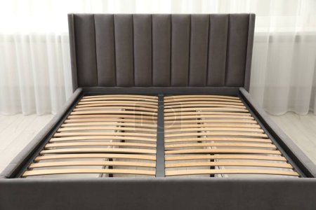 Cama moderna con espacio de almacenamiento para ropa de cama bajo base de listones en la habitación, primer plano