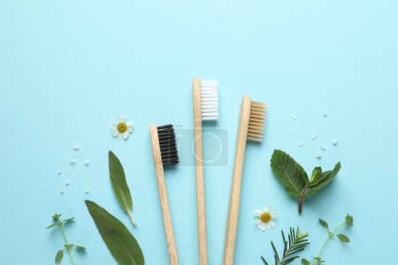 Téléchargez les photos : Brosses à dents en bambou, belles fleurs de camomille, sel de mer et herbes sur fond turquoise, pose plate - en image libre de droit