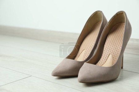 Foto de Plantillas ortopédicas en zapatos de tacón alto en el suelo, primer plano. Espacio para texto - Imagen libre de derechos