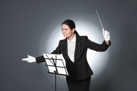 Foto de Conductor profesional feliz con bastón y soporte de notas sobre fondo gris - Imagen libre de derechos
