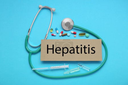 Téléchargez les photos : Carton avec mot Hépatite et fournitures médicales sur fond bleu clair, plat - en image libre de droit