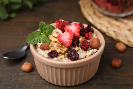 Photo for Oatmeal with freeze dried fruits, nuts and mint on wooden table, closeup - Royalty Free Image