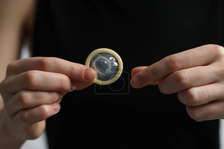 Photo for Woman holding unpacked condom, closeup. Safe sex - Royalty Free Image