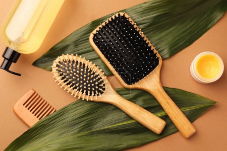 Téléchargez les photos : Composition plate avec brosses à cheveux en bois et produits cosmétiques sur fond brun clair - en image libre de droit
