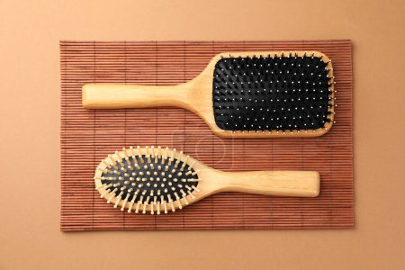 Téléchargez les photos : Brosses à cheveux en bois et tapis de bambou sur fond brun clair, pose plate - en image libre de droit