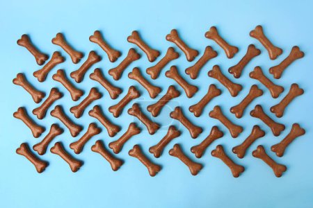 Téléchargez les photos : Composition plate avec biscuits pour chien en forme d'os sur fond bleu clair - en image libre de droit