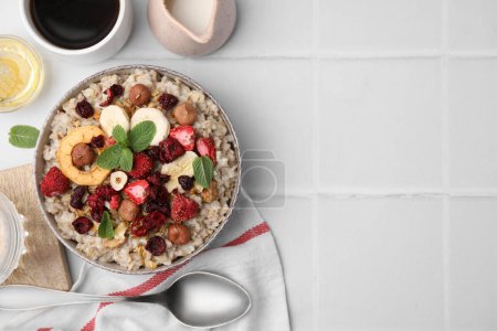 Photo for Oatmeal with freeze dried fruits, nuts and mint on white tiled table, flat lay. Space for text - Royalty Free Image