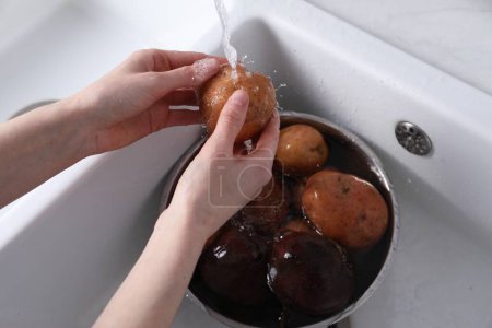 Foto de Mujer lavando papas frescas en el fregadero de la cocina, primer plano. Ensalada de vinagreta para cocinar - Imagen libre de derechos