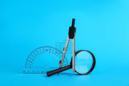 Photo for Protractor, magnifying glass and compass on light blue background - Royalty Free Image