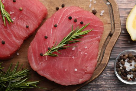 Photo for Raw tuna fillets with rosemary and peppercorns on wooden board, top view - Royalty Free Image