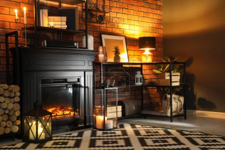 Photo for Beautiful fireplace and different decor in living room at night. Interior design - Royalty Free Image
