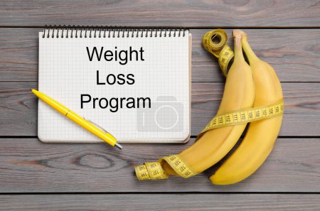 Photo for Notebook with phrase Weight Loss Program, measuring tape and bananas on grey wooden table, flat lay - Royalty Free Image