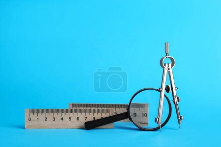 Photo for Rulers, magnifying glass and compass on light blue background - Royalty Free Image