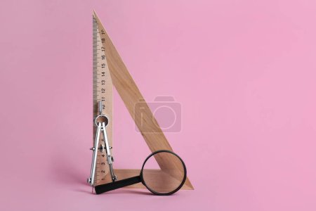 Photo for Triangle ruler, magnifying glass and compass on pink background - Royalty Free Image