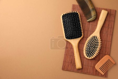 Téléchargez les photos : Brosses à cheveux et peignes en bois sur fond brun clair, pose plate. Espace pour le texte - en image libre de droit