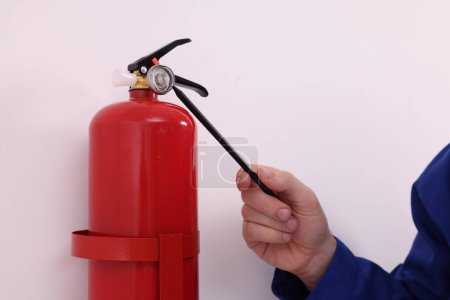 Photo for Man checking quality of fire extinguisher indoors, closeup - Royalty Free Image