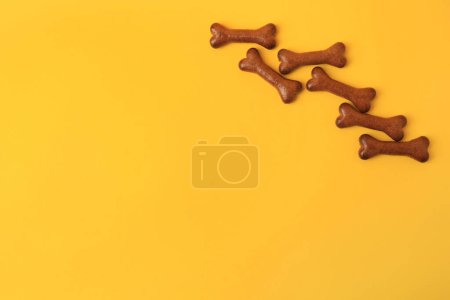 Téléchargez les photos : Biscuits pour chien en forme d'os sur fond orange, plat. Espace pour le texte - en image libre de droit
