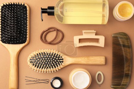 Téléchargez les photos : Composition plate avec brosses à cheveux en bois et différents produits cosmétiques sur fond brun clair - en image libre de droit