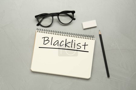 Téléchargez les photos : Liste noire Word écrite en bloc-notes, crayon, lunettes et gomme sur table grise, pose à plat - en image libre de droit
