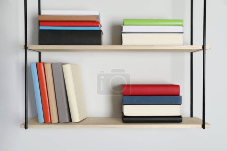 Foto de Estantes con muchos libros de tapa dura en la pared blanca - Imagen libre de derechos