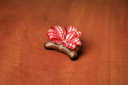Téléchargez les photos : Cookie chien en forme d'os avec noeud rouge sur fond en bois - en image libre de droit